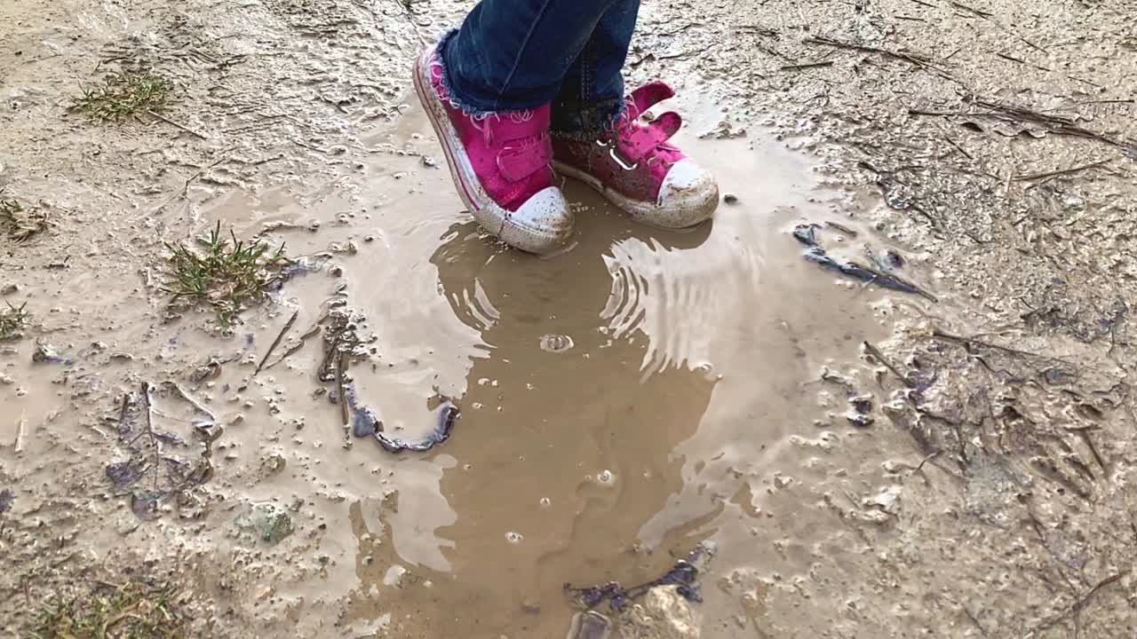 Feet of Little Girl in Pink Shoes Splashing Her Feet in a Muddy Puddle in Slow Motion 1080p