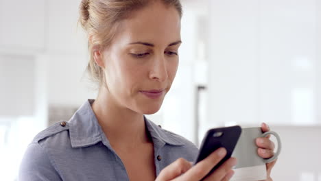mujer real usando teléfono móvil en casa bebiendo café disfrutando de un estilo de vida relajante