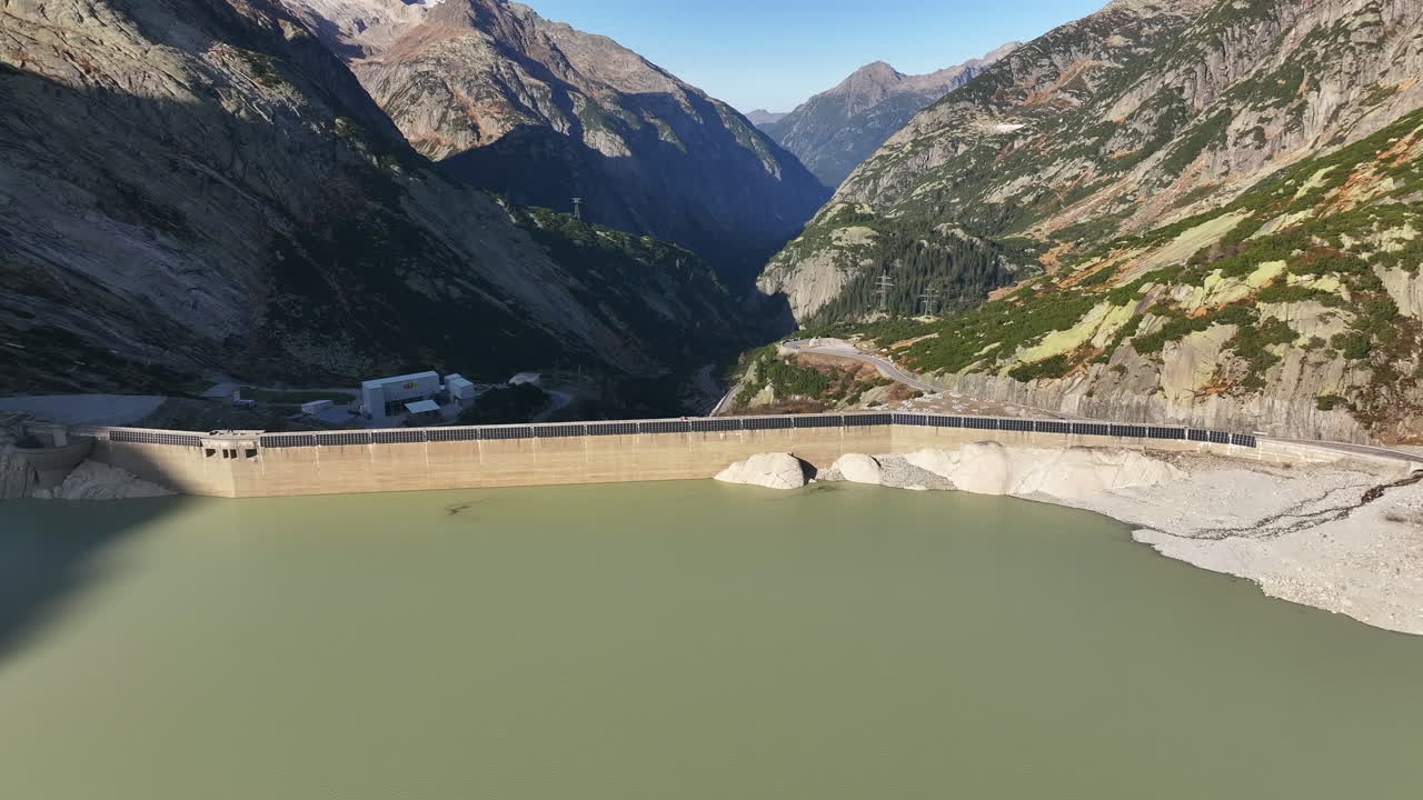 Grimsel dam reservoir with solar panels surrounded by scenic mountains in Switzerland