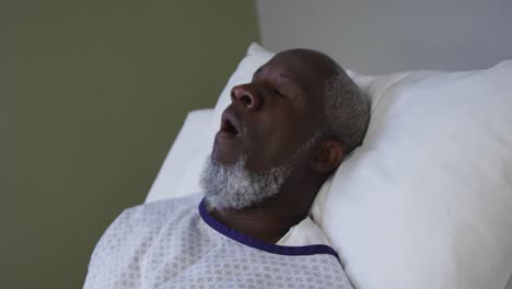 African-american-male-patient-lying-in-hospital-bed-and-yawning