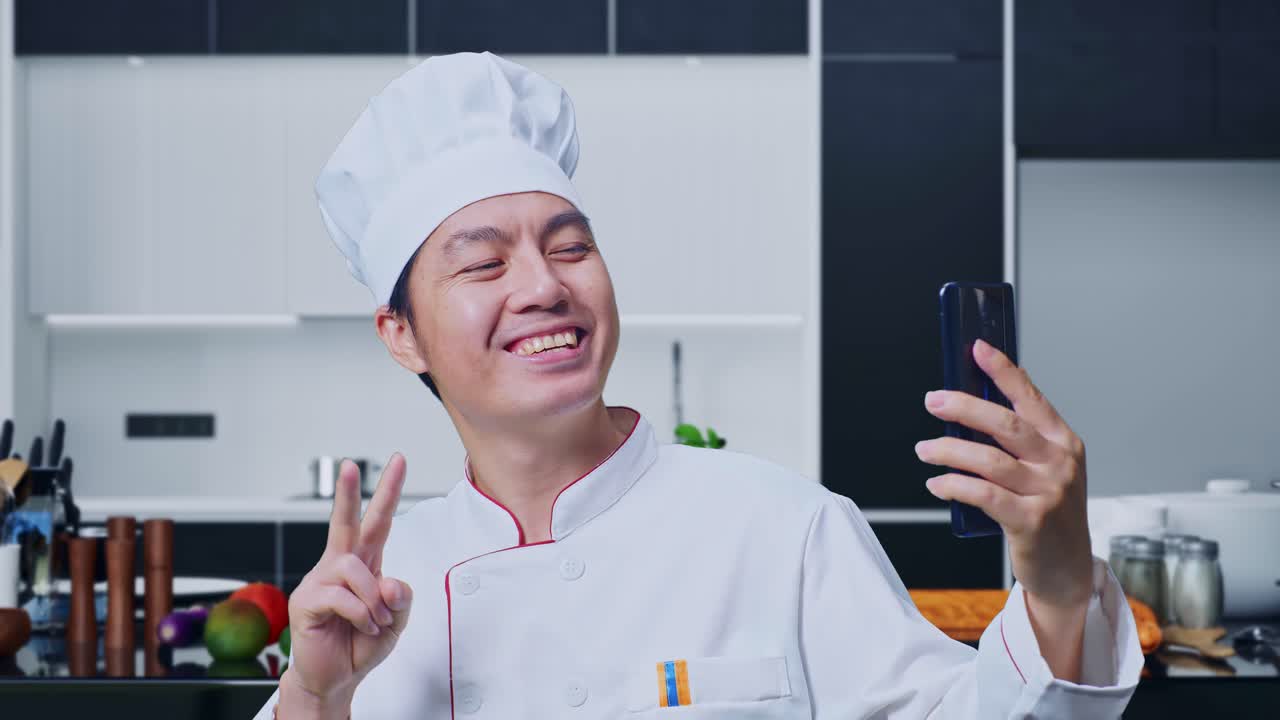 close up de un chef asiático usando un teléfono inteligente tomando una foto mientras está de pie en la cocina de casa