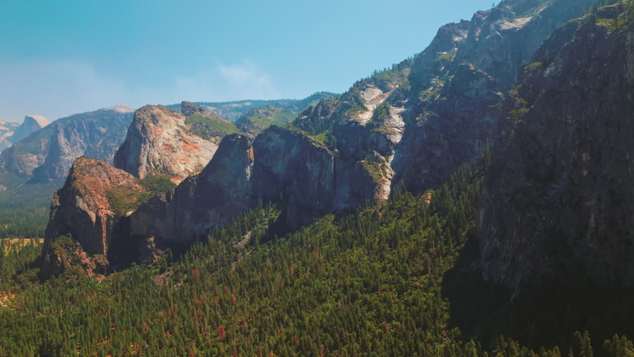 Beautiful rock formations in the United States National Park of Yosemite. Pine tree forest overgrowing the mountains. Sunny day clear sky backdrop.