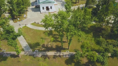 newly wedded couple walks along park near church aerial view