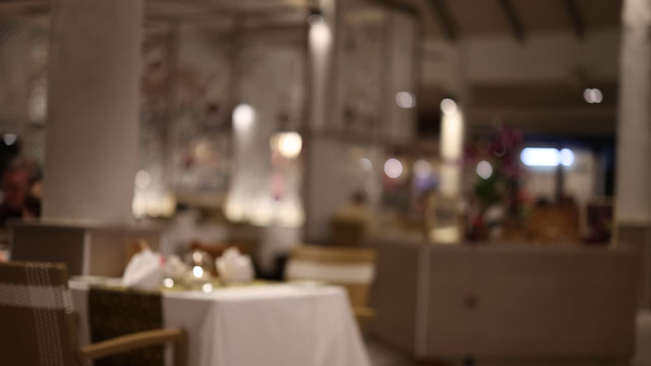A dimly lit restaurant scene with blurred focus, capturing a serene and intimate dining atmosphere in Thailand