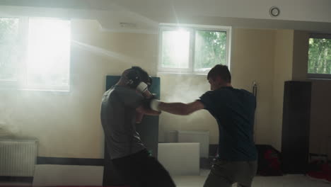 los deportistas entrenan habilidades de combate en el sparring en el club deportivo. los hombres hacen ejercicios de pareja atacándose entre sí en el gimnasio en cámara lenta. los maestros de kickboxing luchan