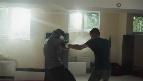 sportsmen train combat skills at sparring in sports club. men couple exercises attacking each other in gym slow motion. kickboxing masters fight