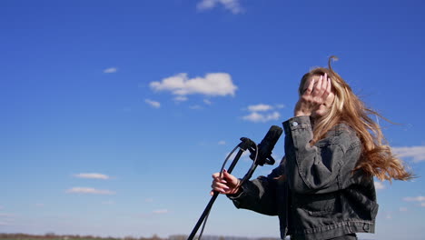attractive pop singer dances outdoors. beautiful young blonde woman in jeans clothes singing into the microphone on the sky background.