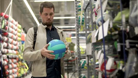 hombre comprando voleibol en una tienda de deportes