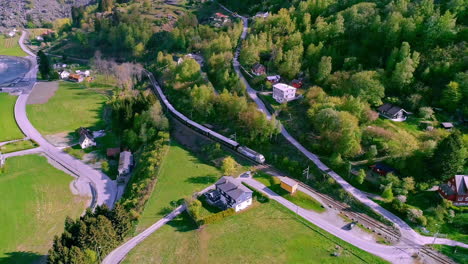 long passenger train driving in the viking valley in norway on a sunny day