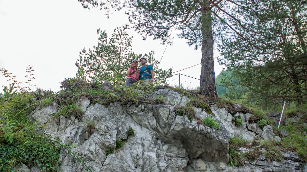 Young couple in climbing gear celebrate climbing a hill