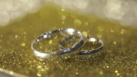 wedding silver rings lying on shiny glossy surface. shining with light. close-up