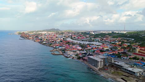 Punda-Pietermaai-coastline-at-sunrise-over-water-and-vibrant-colorful-buildings,-aerial