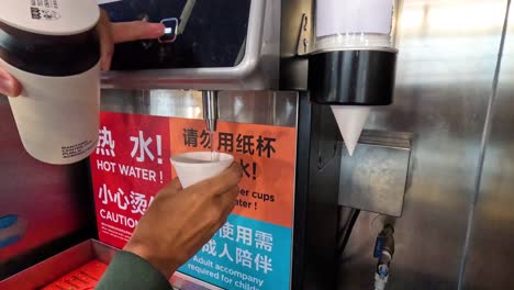 person using hot water dispenser at airport