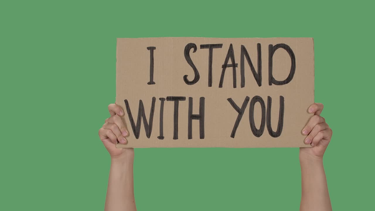 "나는 당신과 함께 서있다""라는 문구가 새겨진 항의 포스터: 인권 자유 운동을 묘사하는 배경, 포스터를 들고 있는 여성 손, 녹색 스크린, 크로마 키, 클로즈업, 느린 모션"