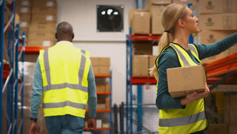 manager with digital tablet in warehouse training female intern standing by shelves