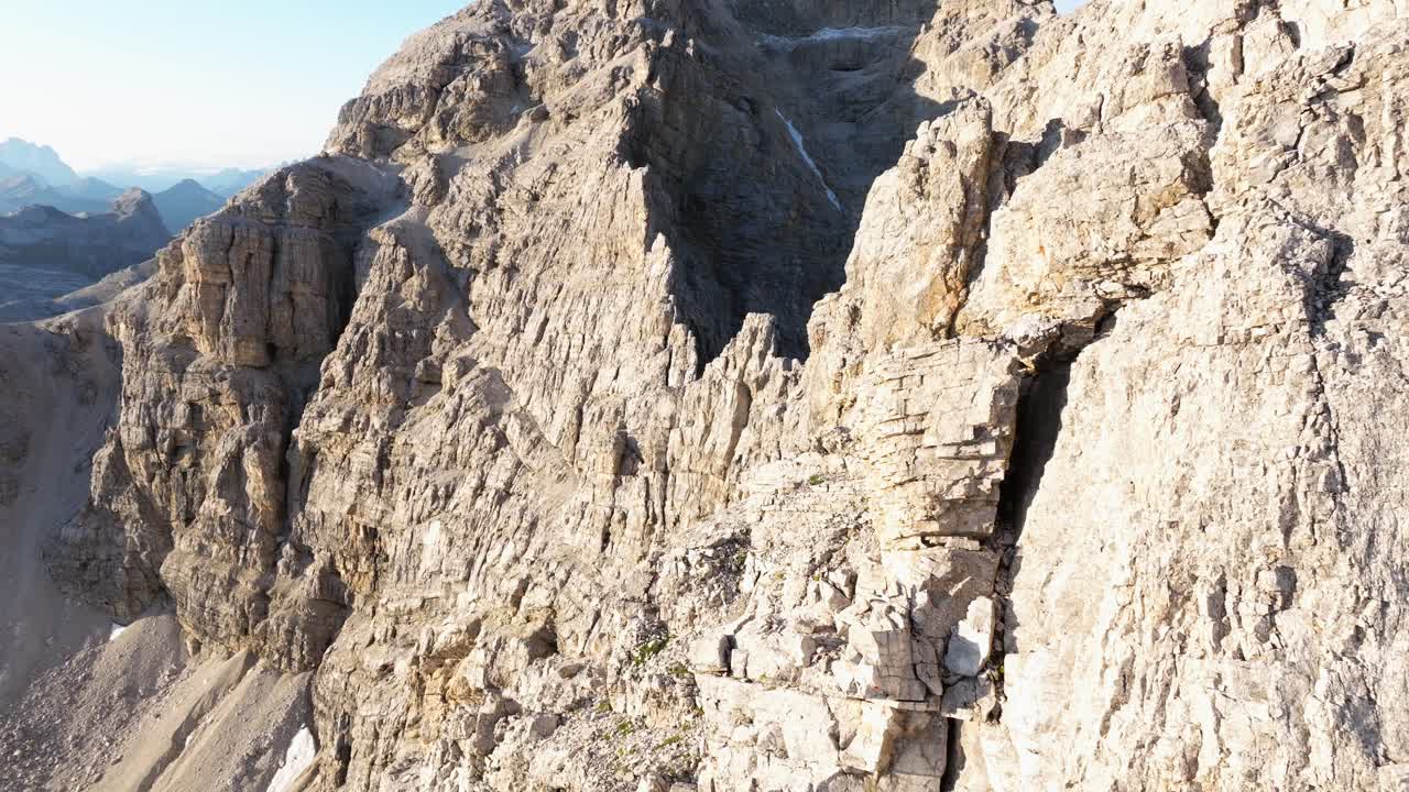 Close-up of Dolomites' textured cliffs, showcasing sunlit stratified rock layers against a clear sky backdrop