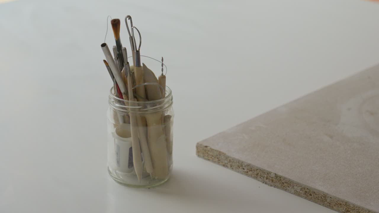 장인 은 점토 를 미술품 으로 바꾸기 위해 조각 도구 를 능숙 히 선택 한다