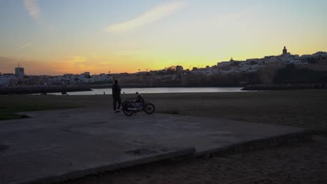 Mann,-Der-Einen-Kaffee-Trinkt-Und-Den-Sonnenuntergang-In-Der-Nähe-Seines-Motorrads-Genießt
