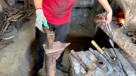 ajustar la cuchilla de metal en un taller de trabajo de hierro afilar herramientas agrícolas para cortar ramas de árboles mango de madera y golpear el rojo derretir metal fundido fuera del horno de carbón caliente en oriente medio asia irán