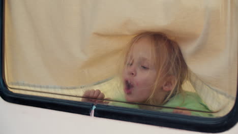 little girl drawing heart on window in a van