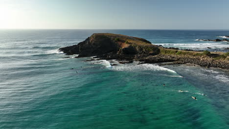 Early-morning-surfers-off-Cresent-Head-Beach-in-New-South-Wales,-Australia