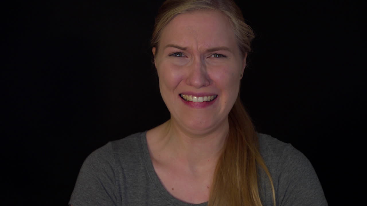 Sorrow and regret. Young blonde-haired woman on a black background cries and screams in despair. Sad woman in depression