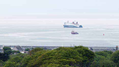 shot of a ferry sailing away from a large fishing boat near the port village of stornoway