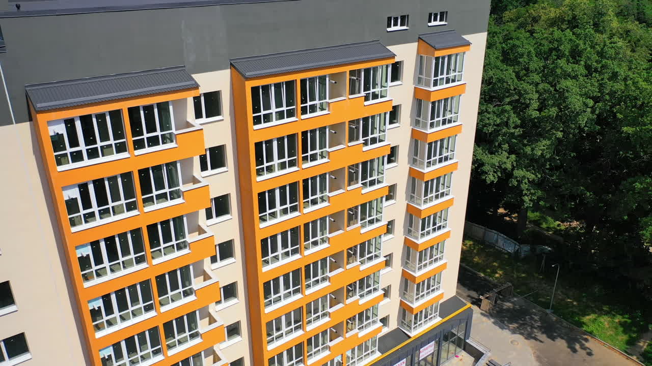 Modern office building in the city. Exterior of a new apartment building with colorful walls and large balconies. Top down drone movement.