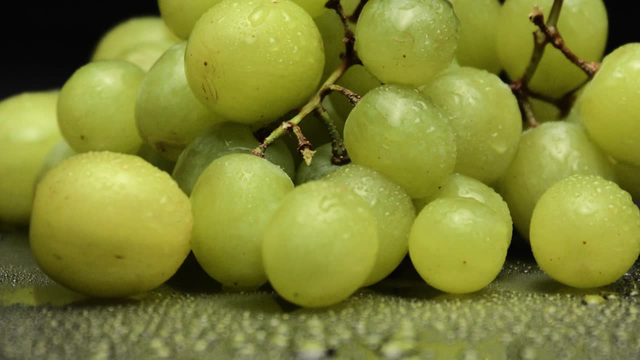 racimo de deliciosas uvas verdes aislado sobre fondo negro