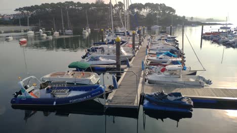 Pleasure-boats-moored-in-the-dock-of-the-port-with-access-by-the-ramp-to-the-platform-at-dawn-and-sunny-summer,-shooting-upplane