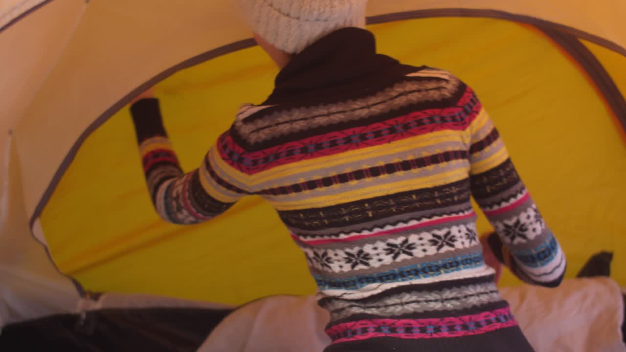 모자와 스웨터를 입은 여자가 녹색 배경을 바라보며 내부에서 텐트를 열고, 여성이 텐트, chromakey를 열고, 겨울 여행 wanderlust