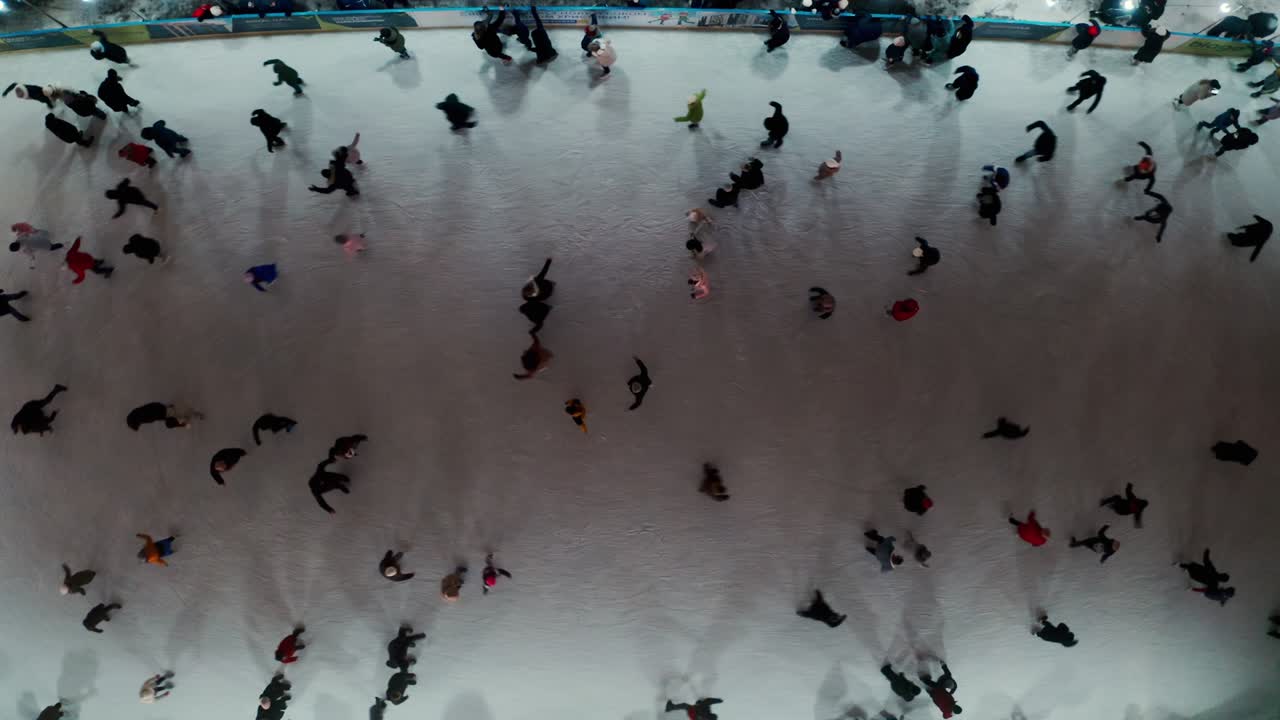 도시에서 야외 스케이트링 링크에서 스케이트를 타는 사람들의 드론 뷰, 어두운 야간 조명.