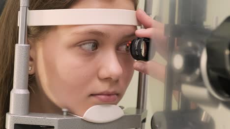 oftalmólogo chequea la vista de un adolescente con equipos modernos. médico chequeando los ojos con un dispositivo de biomicroscopio. toma de dolly de una doctora examinando la estructura del ojo con la ayuda de equipos médicos