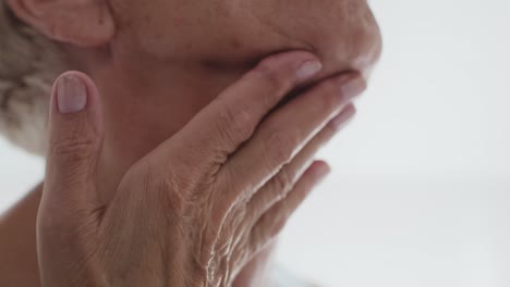 mujer mayor de cerca aplicando una crema facial en el cuello