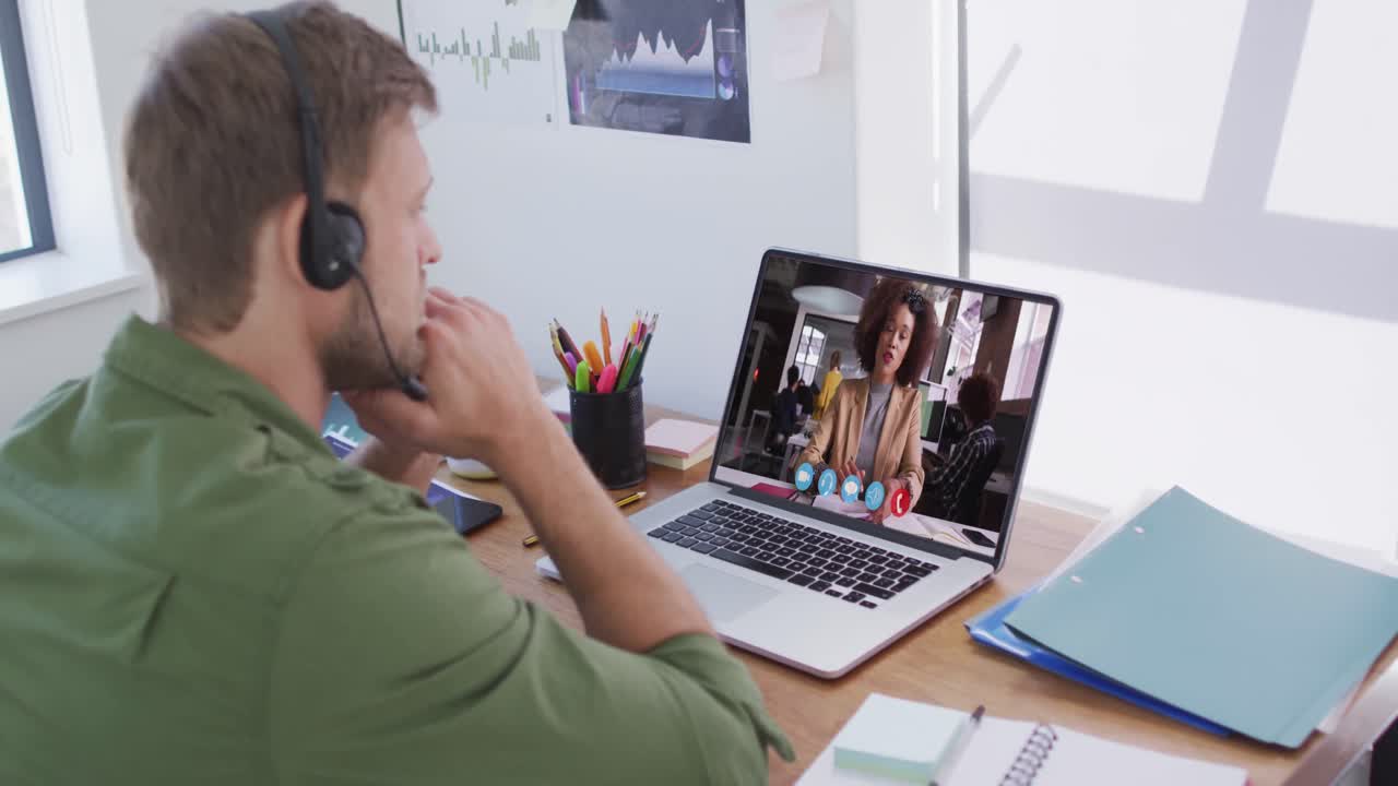 En kaukasisk mand med telefonheadset holder et videomøde med en kvindelig kollega på sin bærbare computer på kontoret.