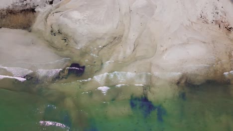 aerial: top down shot of ocean and patterns in the sand