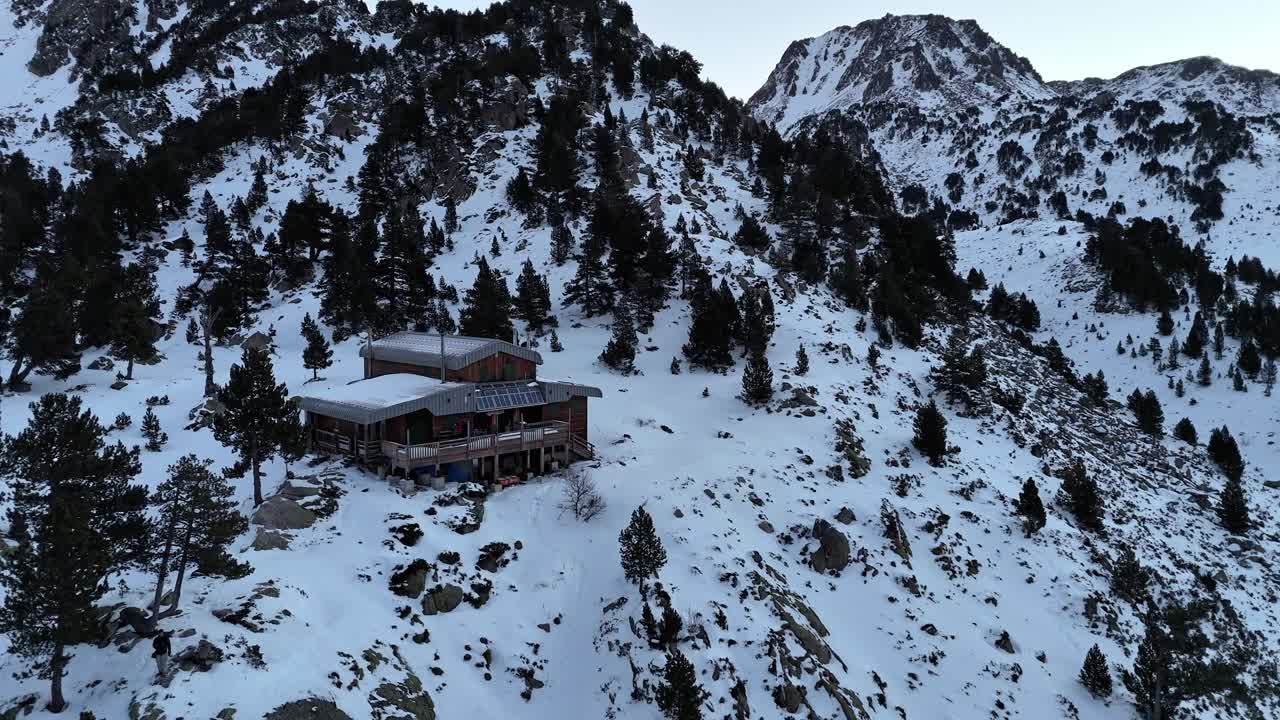 imágenes de drones de un refugio de montaña bajo la nieve al amanecer en las montañas de los pirineos