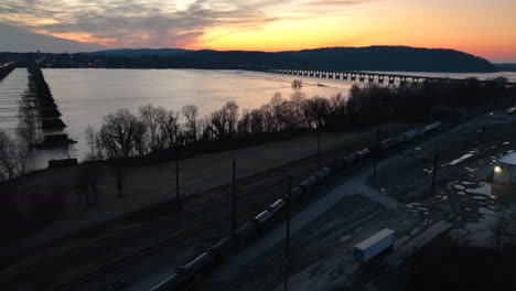 tren de ferrocarril en la noche viaja en vías al lado del río