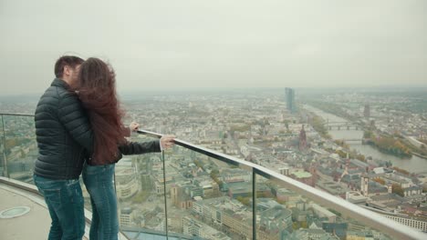 couple is standing on roof of high building of skyscraper in city of megapolis.