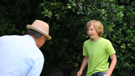 hombre y hijo jugando con una pelota de fútbol en el jardín