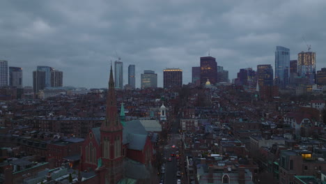 Aerial-descending-footage-of-residential-urban-neighbourhood-at-twilight.-Modern-high-rise-office-buildings-in-background.-Boston,-USA