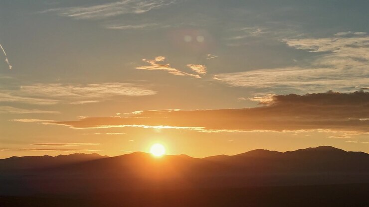 Time-lapse in 4K ripreso da un drone di una splendida alba che sorge su una catena montuosa del sud-ovest. La luminosa luce mattutina crea un distinto alone solare atmosferico tra vivaci nuvole arancioni