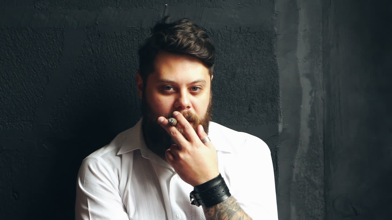 Uomo che fuma una sigaretta. Giovane uomo barbuto che svapa con una sigaretta sullo sfondo