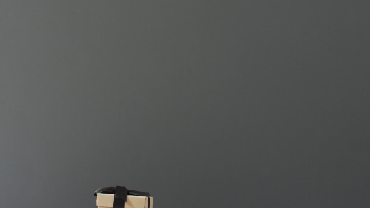 Brown gift box with black ribbon on dark grey background with copy space