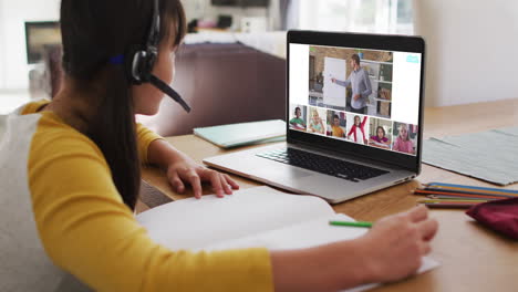 estudiante que usa una computadora portátil para una lección en línea en casa, con un maestro y una clase diversos en la pantalla