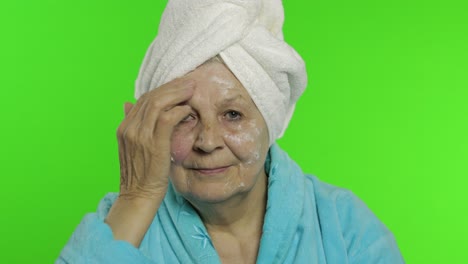 Abuela-Anciana-En-Bata-De-Baño.-Anciana-Aplicando-Crema-Hidratante-En-La-Cara.