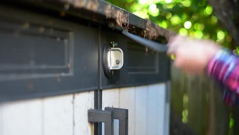 Beautifully-shot-close-up-of-a-padlock-and-latch-on-a-shed-with-hands-reaching-in-to-use-a-key-to-unlock-and-remove-the-lock-and-open-up-the-shed,-with-stylish-bokeh