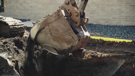 close up of excavator digging a hole, picking up dirt soil in bucket