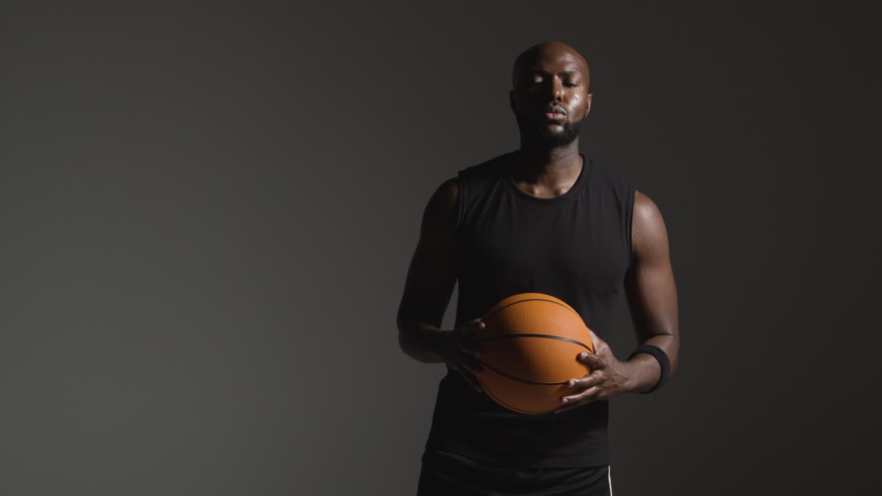 retrato de estudio de un jugador de baloncesto caminando hacia la cámara sosteniendo el balón