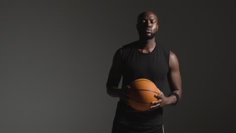 retrato de estudio de un jugador de baloncesto caminando hacia la cámara sosteniendo el balón
